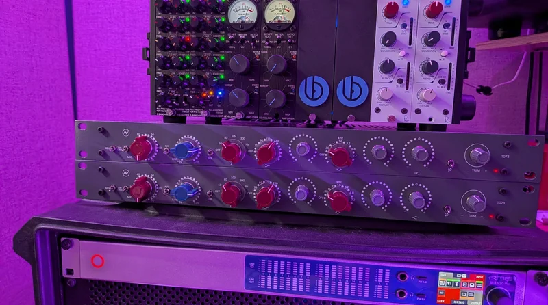 Two completed AML EZ1073 mic preamp units on the studio workbench, warm light catching the front panels